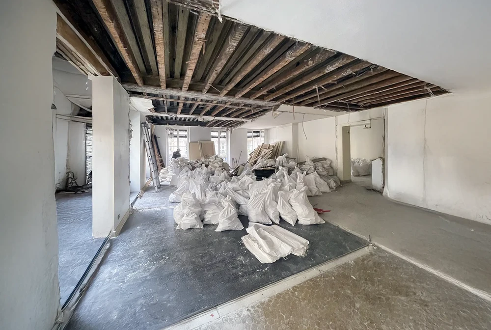Chantier de rénovation intérieure d'un appartement avec plafond démoli exposant les poutres et solives en bois