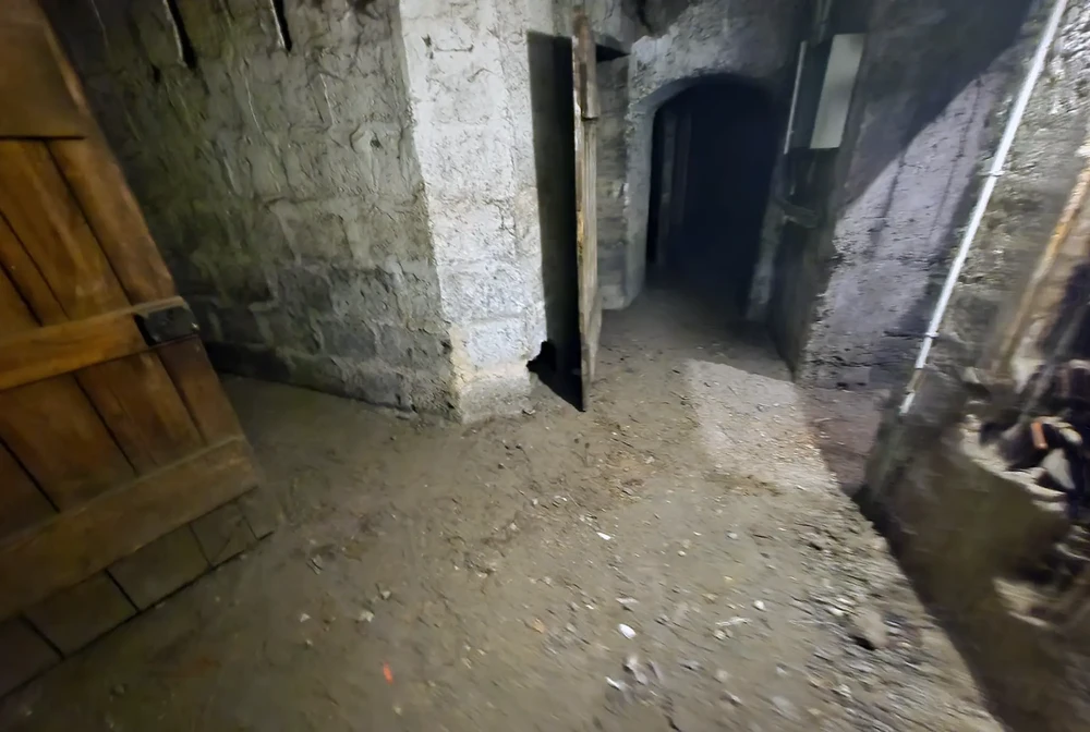 Cave voûtée en pierre avec murs en moellons calcaires et sol en terre battue