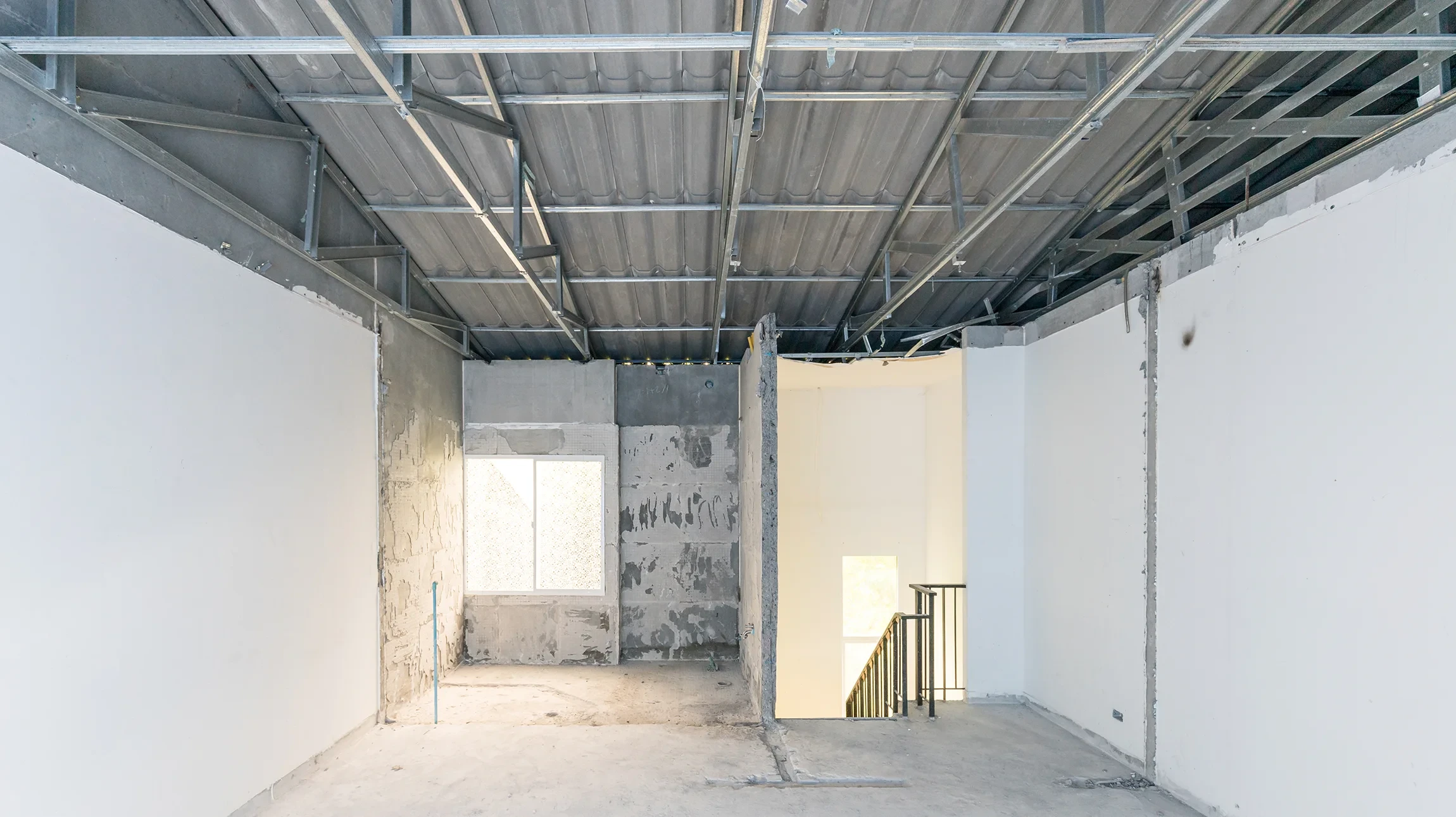 Une pelleteuse hydraulique orange effectue la d&eacute;molition d'un mur en briques rouges dans un environnement r&eacute;sidentiel ext&eacute;rieur