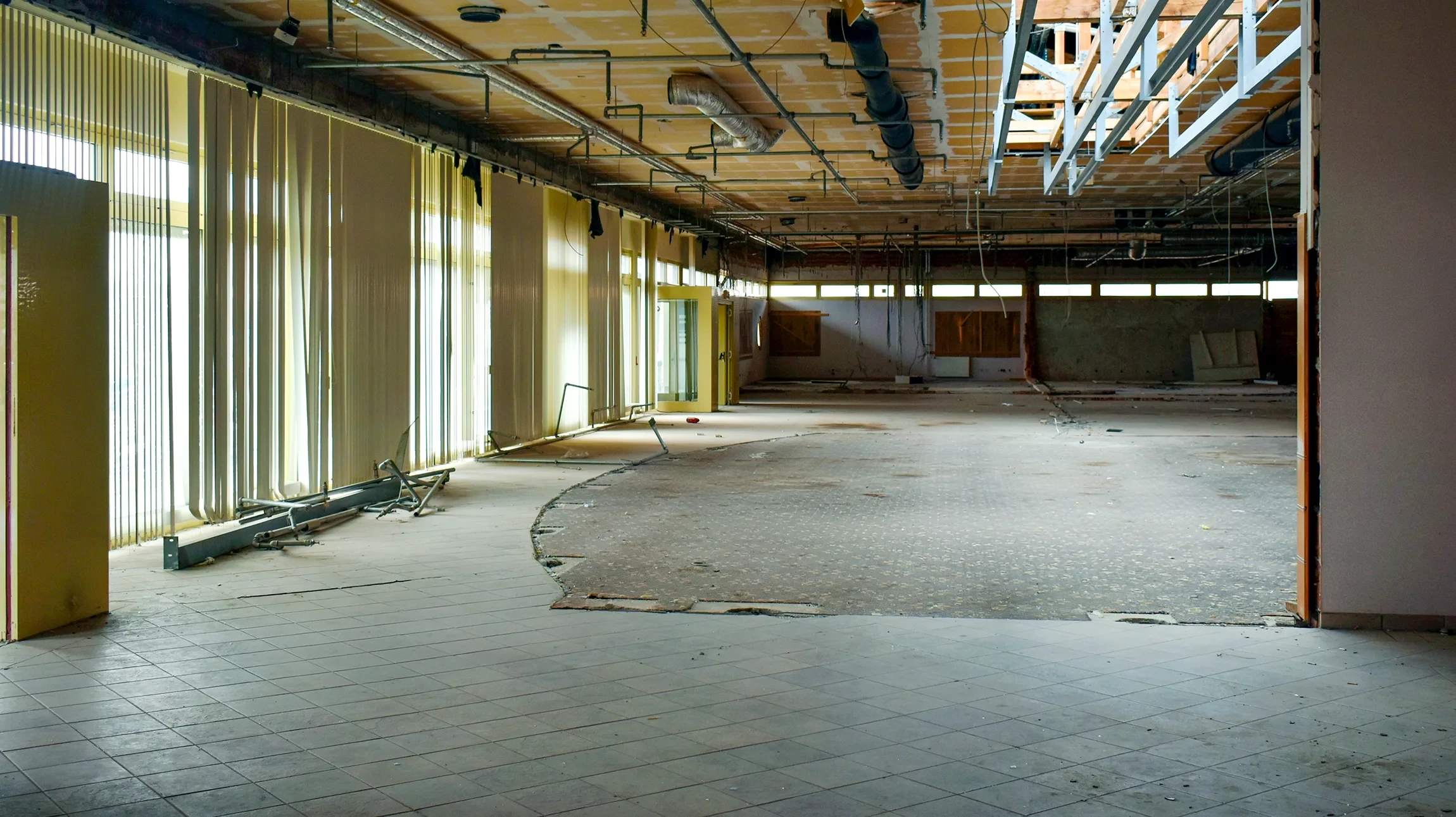 Ouvrier en équipement de sécurité orange travaillant sur chantier extérieur, agenouillé près d'une plaque vibrante compacteuse jaune