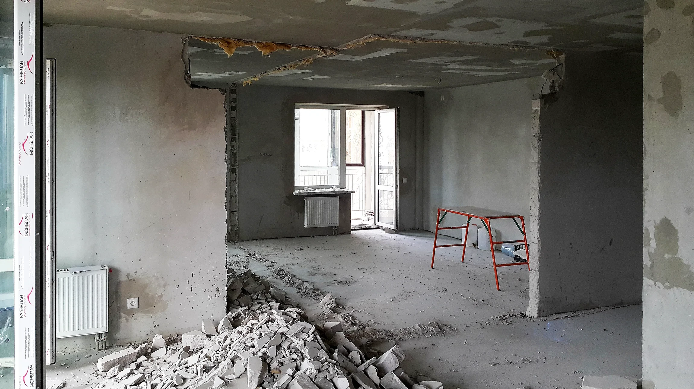 Ouvrier en démolition intérieure utilisant un marteau-piqueur pneumatique pour abattre un mur en briques