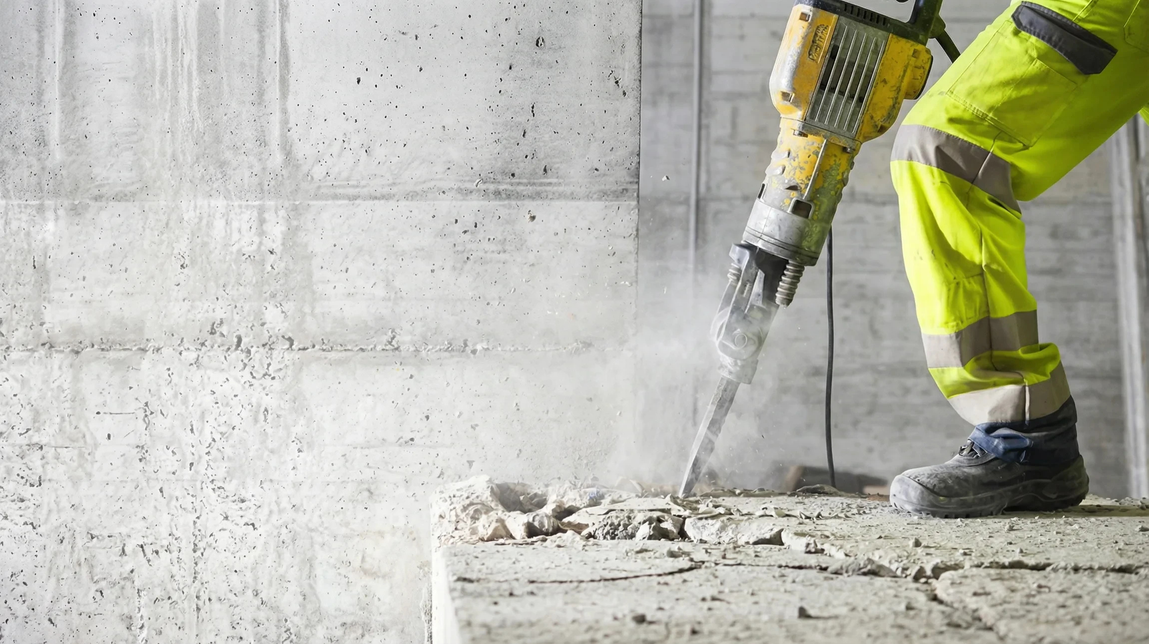 Chantier de démolition en extérieur avec pelleteuse équipée d'un godet casseur manipulant des gravats de béton et briques